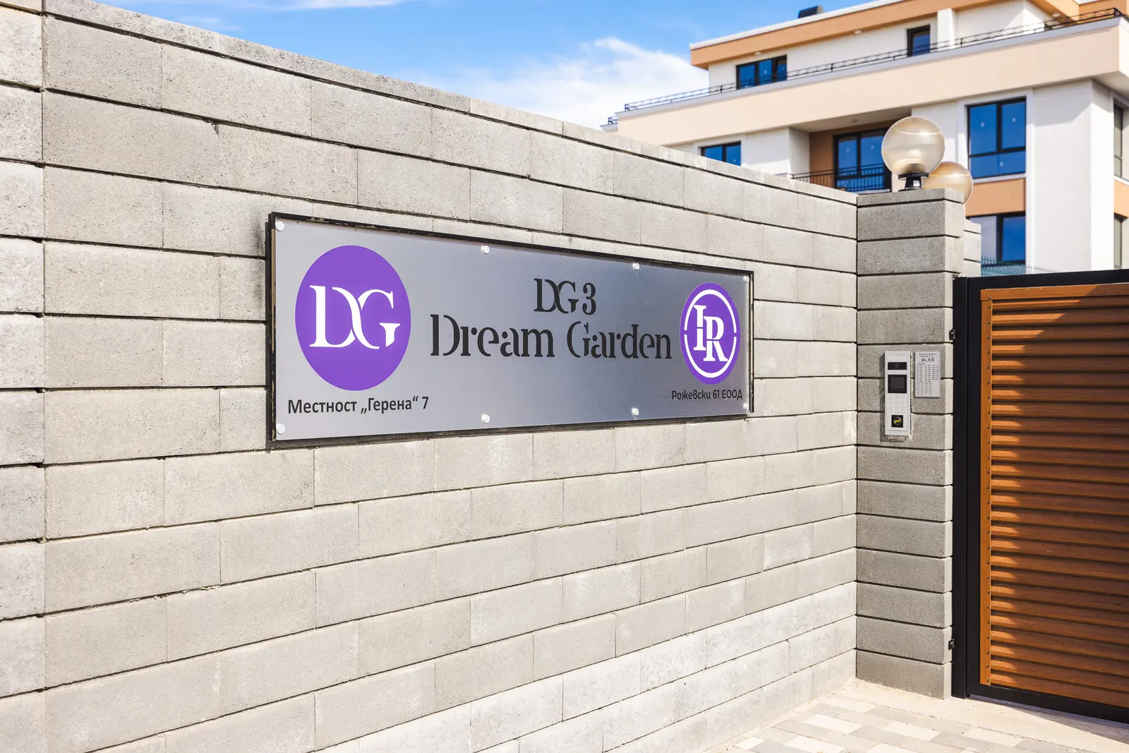 Табелата на Dream Garden 3 върху каменната ограда при входа
